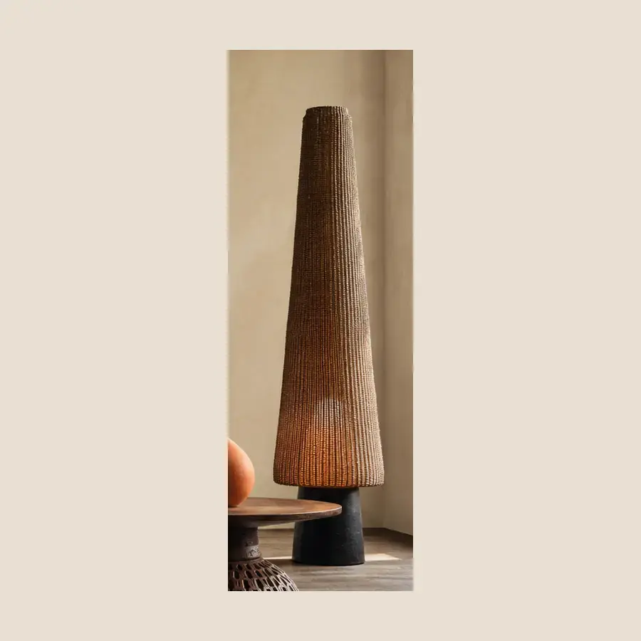 Lampe Tressée — Lampadaire conique en fibres tressées, diffusant une lumière chaude et filtrée.