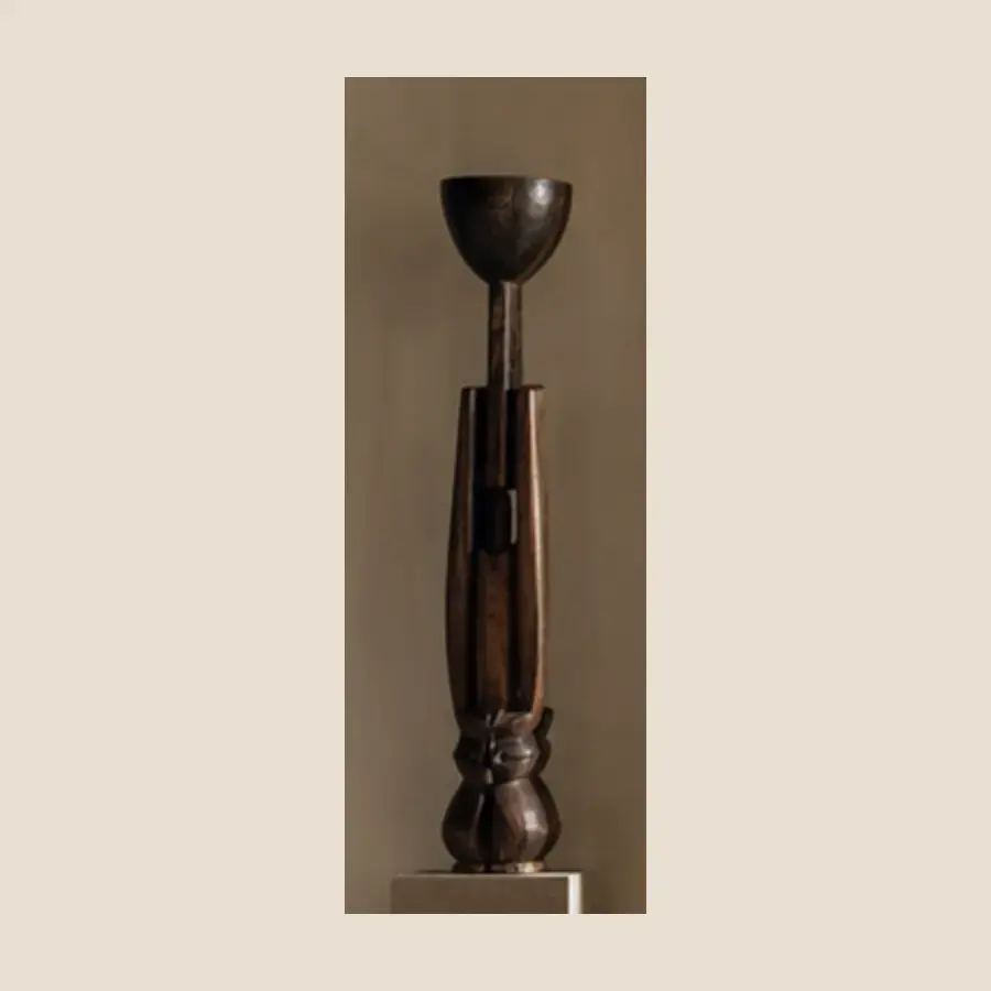Totem Sombre — Totem sculpté aux anneaux superposés, patine profonde, présenté sur socle de pierre claire.